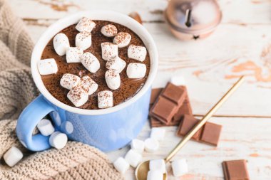 Marşmelovlu bir fincan sıcak çikolata ve ahşap masada Noel dekoru.