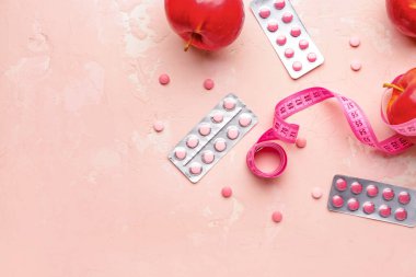 Renk arka planında mezura, elma ve kilo kaybı hapları ölçülüyor