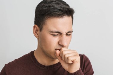 Hafif arka planda öksüren genç adam