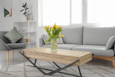 Masasında bir buket bahar çiçeği olan modern odanın içinde.