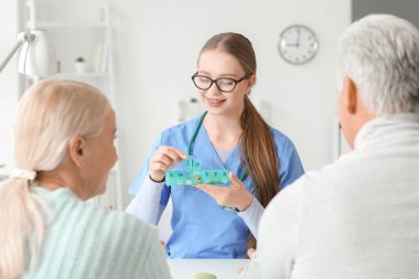Doktor klinikteki yaşlı çifte hap veriyor.