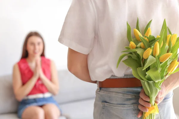 Jongeman Met Bloemen Voor Mooie Vriendin Achter Zijn Rug Thuis — Stockfoto