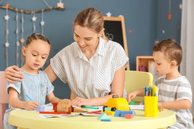 Evde oynayan ve resim çizen sevimli çocukları olan bir dadı.