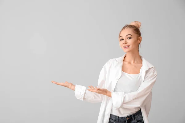 Schöne Junge Frau Zeigt Etwas Auf Grauem Hintergrund — Stockfoto