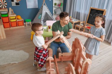 Baba ve küçük çocuklar evlerinde yemek dağıtım evleriyle oynuyorlar.