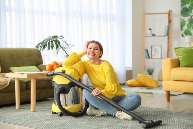 Evde elektrikli süpürgesi olan genç bir kadın.