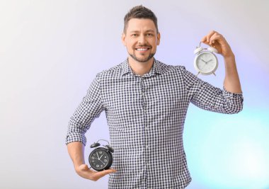 Işıklı arka planda çalar saati olan bir adam. Zaman yönetimi kavramı