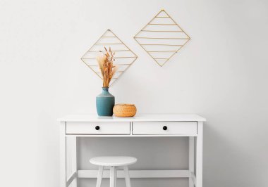 Beyaz duvarın yanındaki odada sepetli vazo.