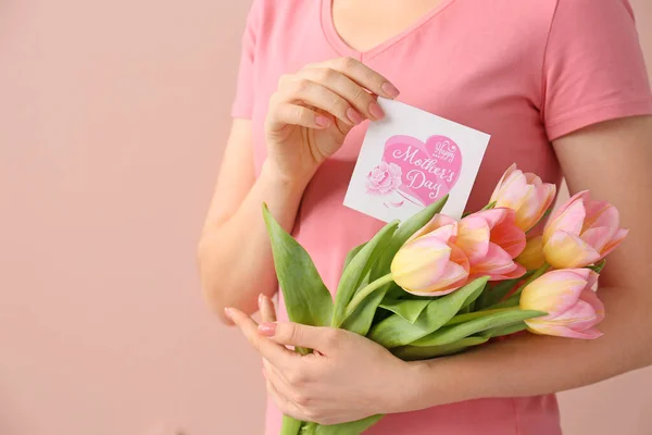 Frau Hält Grußkarte Und Blumen Zum Muttertag Auf Farbigem Hintergrund — Stockfoto