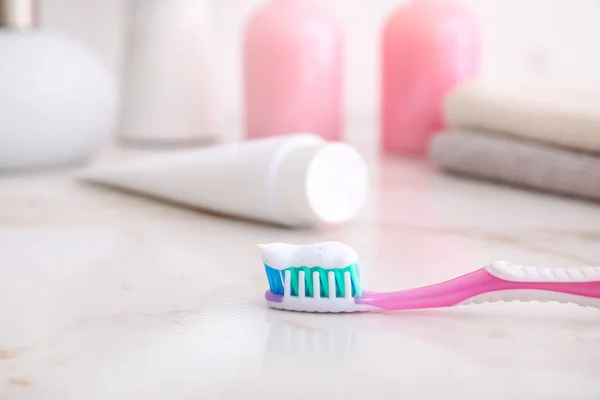 Tooth brush with paste on table in bathroom