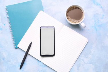 Cep telefonu, kahve fincanı ve renk arkaplanı kırtasiyesi.