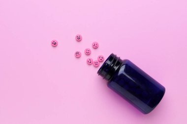 Renkli arka planda yüzleri çizilmiş şişe ve haplar