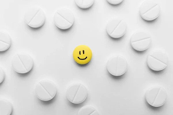白いものの中で幸せな顔を描いた黄色の丸薬 トップビュー — ストック写真
