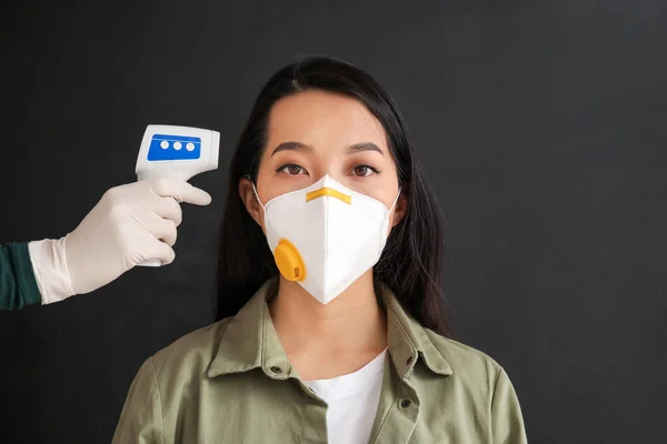 暗い背景に保護マスクでアジアの女性の温度を測定医師 コロナウイルス流行の概念 — ストック写真