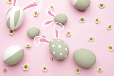 Güzel Paskalya yumurtaları çizilmiş tavşan kulakları ve renkli arka planda çiçekler