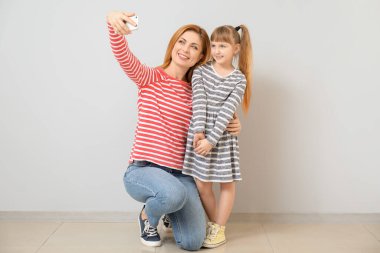 Kadın ve küçük kızı ışık duvarının yanında selfie çekiyorlar.