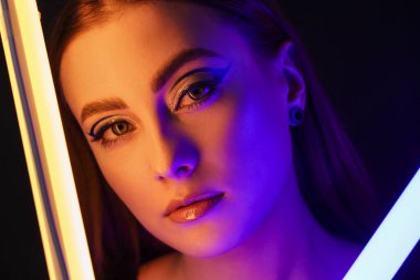 Koyu arkaplanda neon lambaları olan güzel bir kadının tonlu portresi.