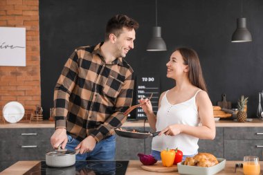Genç çift mutfakta birlikte yemek pişiriyor.