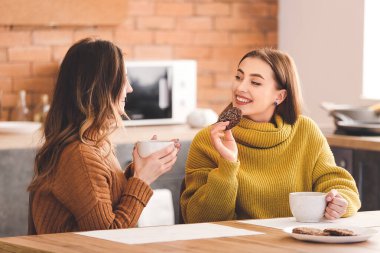 Genç kadınlar mutfakta çay içiyor.