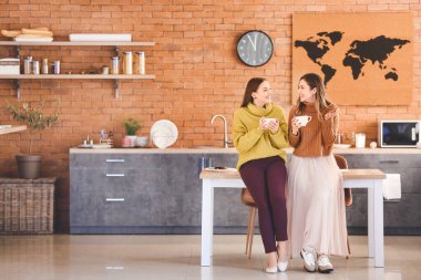 Genç kadınlar mutfakta çay içiyor.