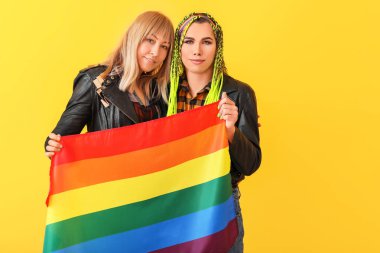 Renkli arka planda LGBT bayrağı taşıyan genç transseksüel çiftin portresi