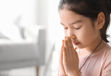 Evde dua eden sevimli küçük Asyalı kız.