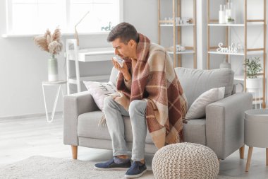 Evde öksüren genç adam.