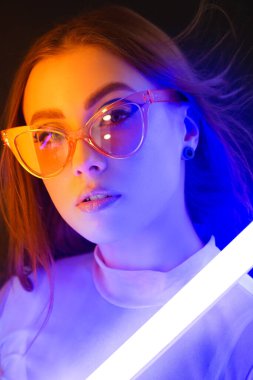 Koyu arkaplanda neon lambalı güzel bir kadının tonlu portresi.