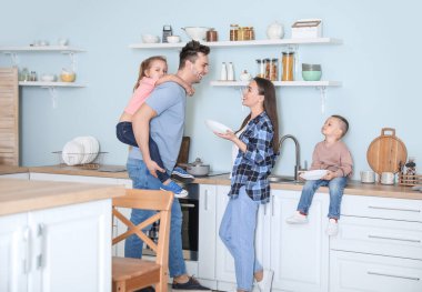 Genç aile mutfakta bulaşık yıkıyor.