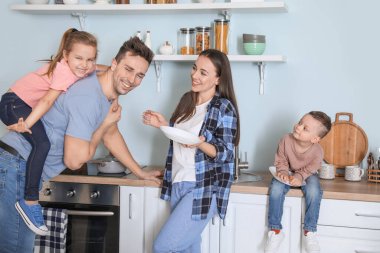 Genç aile mutfakta bulaşık yıkıyor.
