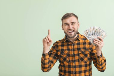 Parası olan yakışıklı bir genç ve arka planda işaret parmağı kaldırmış.