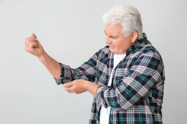 Gri arka planda Parkinson sendromu olan yaşlı bir adam.