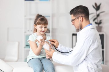 Küçük kız nasıl klinikte stetoskop kullanılacağını gösteren oyuncak çocuk doktoru