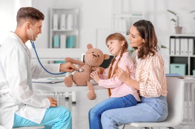 Küçük kız nasıl klinikte stetoskop kullanılacağını gösteren oyuncak çocuk doktoru