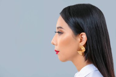 Gri arkaplanda güzel saçları olan genç Asyalı kadın.