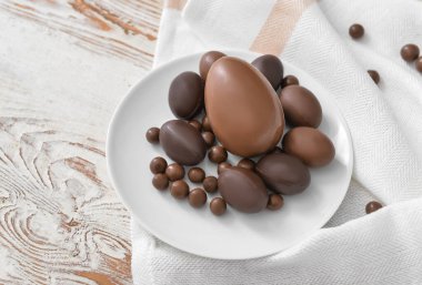 Tabakta çikolatalı yumurta ve ahşap masa şekeri var.