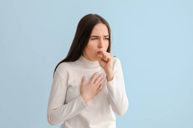 Hafif arka planda öksüren genç kadın.