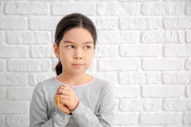 Beyaz arka planda dua eden tatlı küçük Asyalı kız.