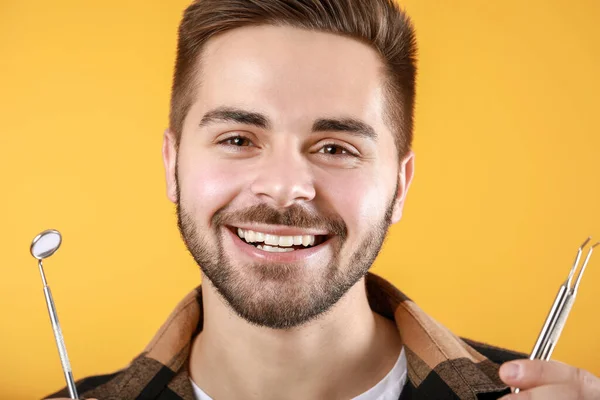 Счастливый Улыбающийся Молодой Человек Инструментами Дантиста Цветном Фоне — стоковое фото