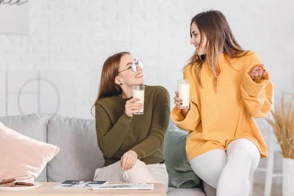 暖かいセーターの若い女性は自宅で牛乳を飲む — ストック写真