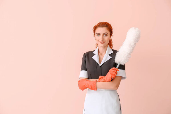 Beautiful young chambermaid on color background