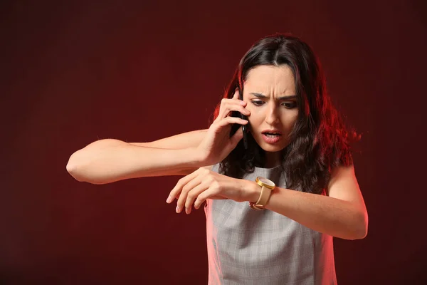 Mujer Preocupada Mirando Reloj Mientras Habla Por Teléfono Sobre Fondo —  Fotos de Stock