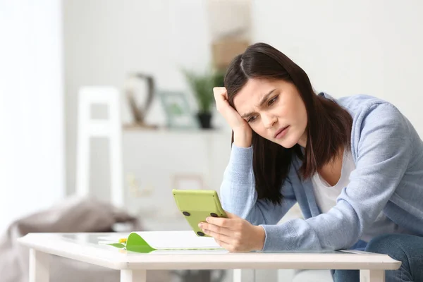 Young woman with calculator at home