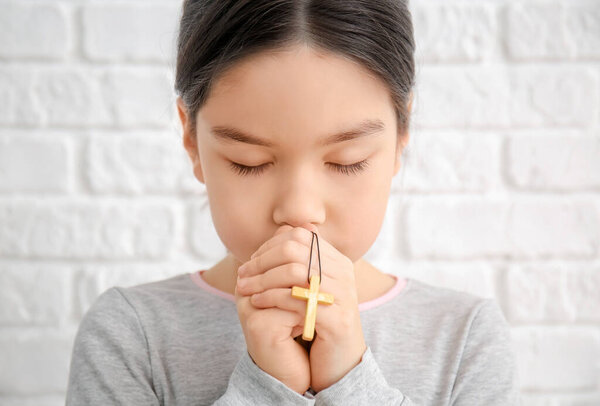 Cute little Asian girl praying on white background