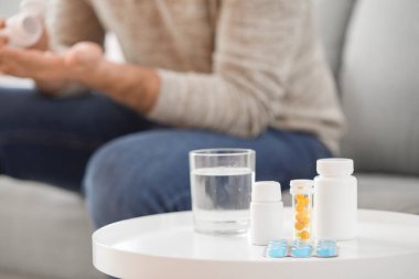 İlaçlar ve bir bardak su masada.