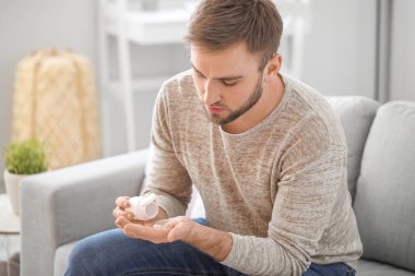 Genç adam evde ilaç alıyor.