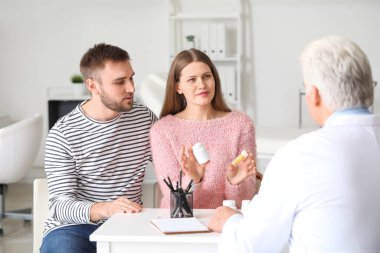 Doktor klinikteki genç çifte ilaç veriyor.