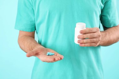 Renkli arka planda hapları olan genç adam, yakın plan.