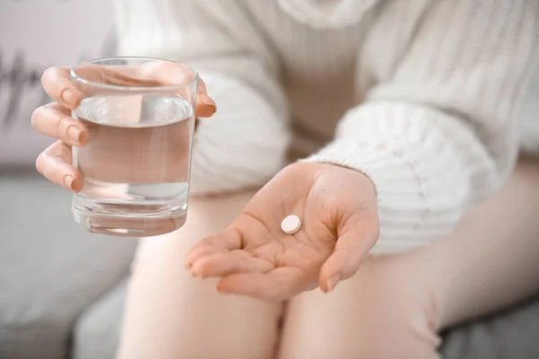 Young woman taking medicine at home, closeup