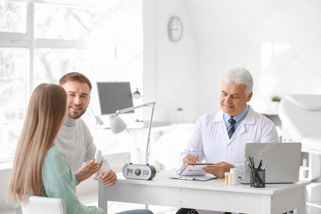 Doctor giving pills to young couple in clinic